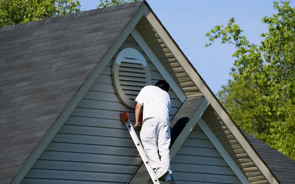 A painter working on the gable of a house exterior