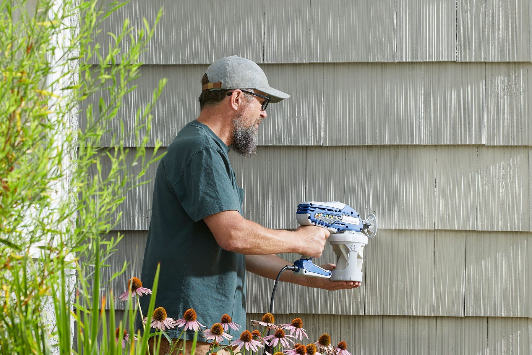 A painter spray-finishing exterior siding